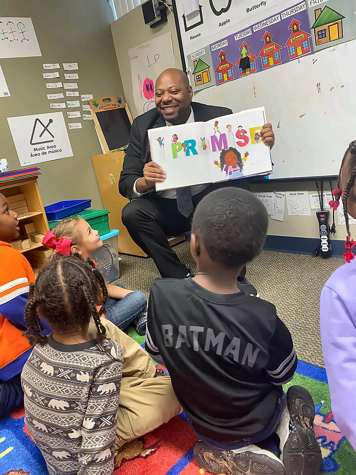 Kermit Williams reading a book to young students in a classroom