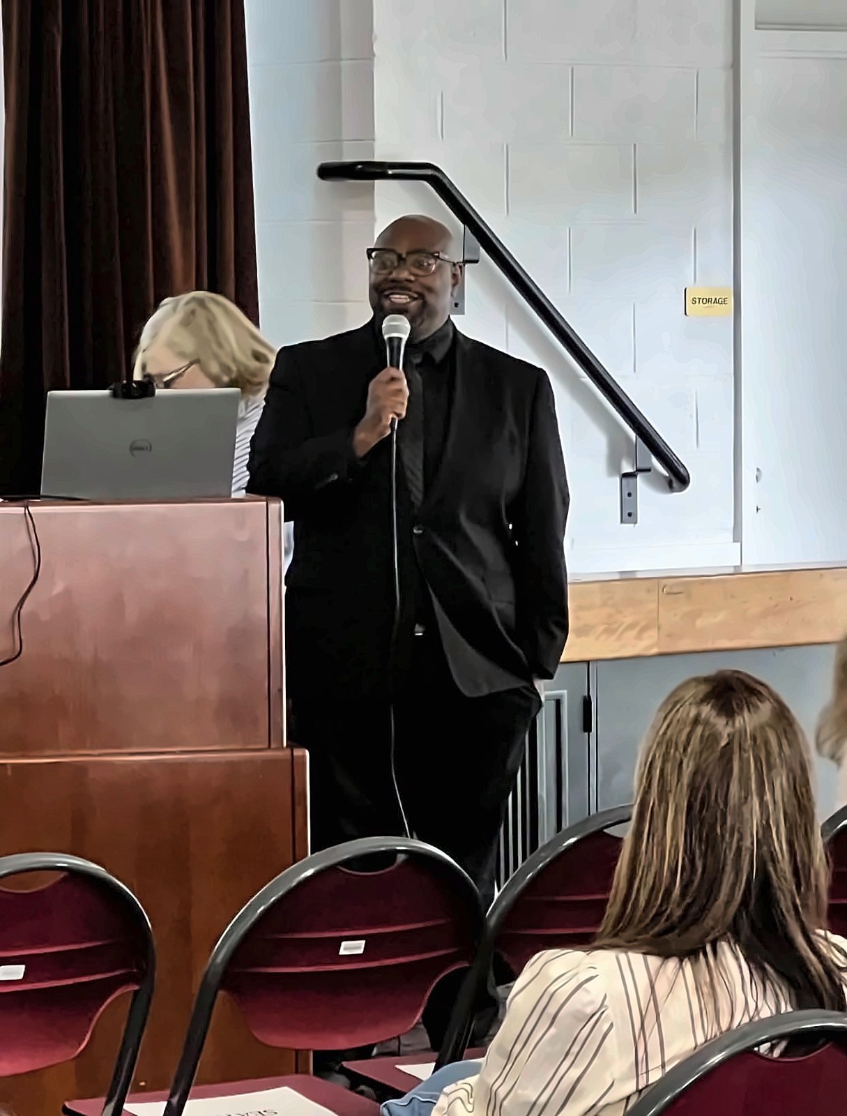 Kermit Williams speaking with a microphone to a seated audience